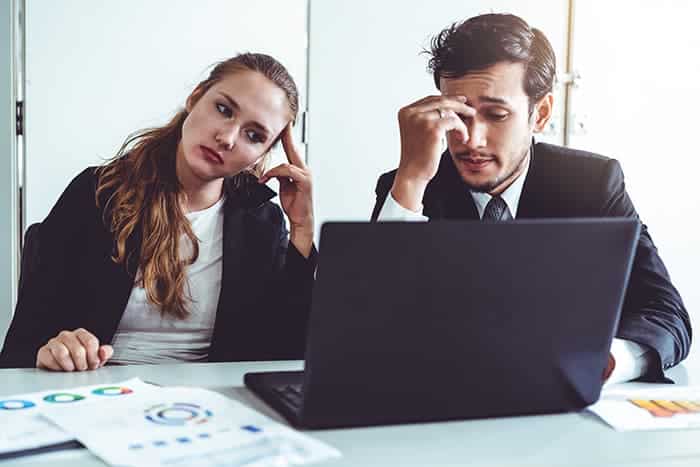 Unhappy serious businessman and businesswoman working using laptop computer on the office desk. Bad business crisis situation and bankruptcy concept